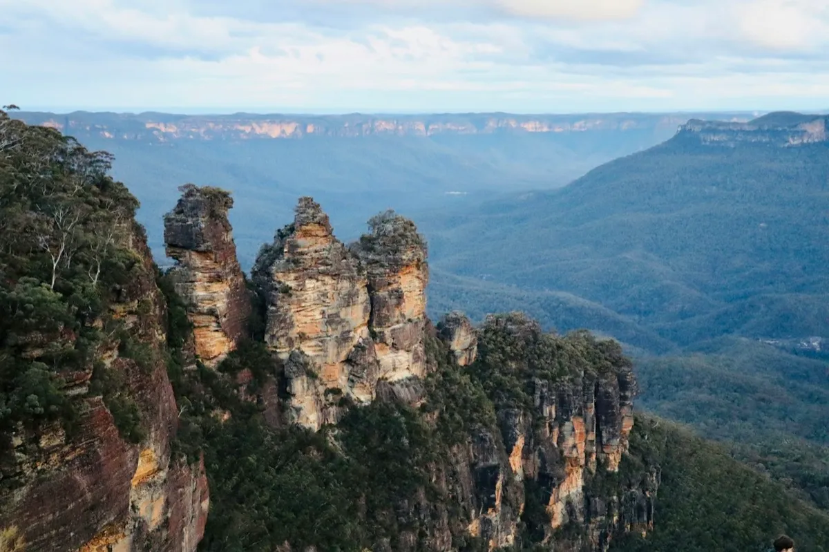Three sandstone pillars above a forested valley